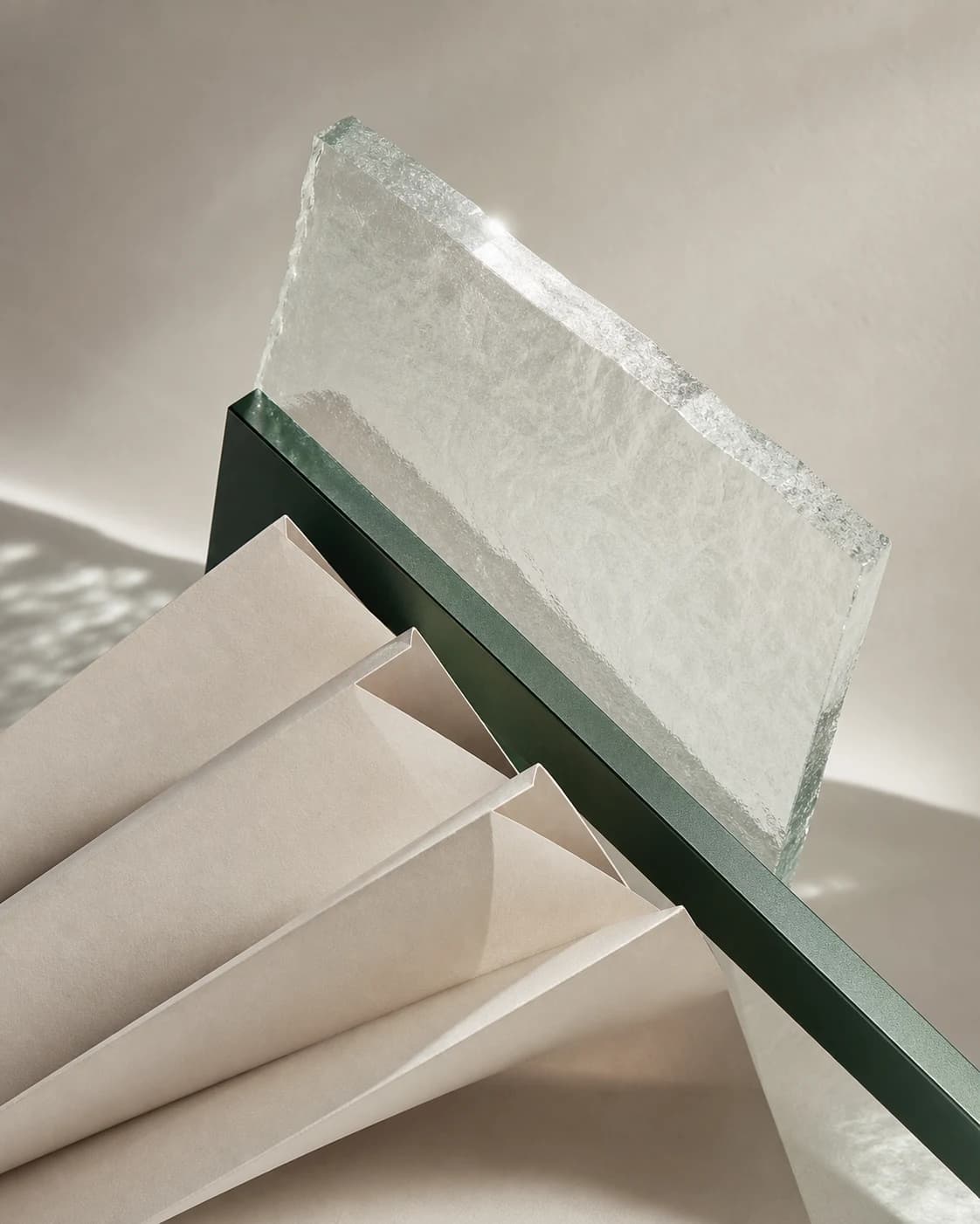 Glass, paper and a dark green metal plane arranged in a precise material study